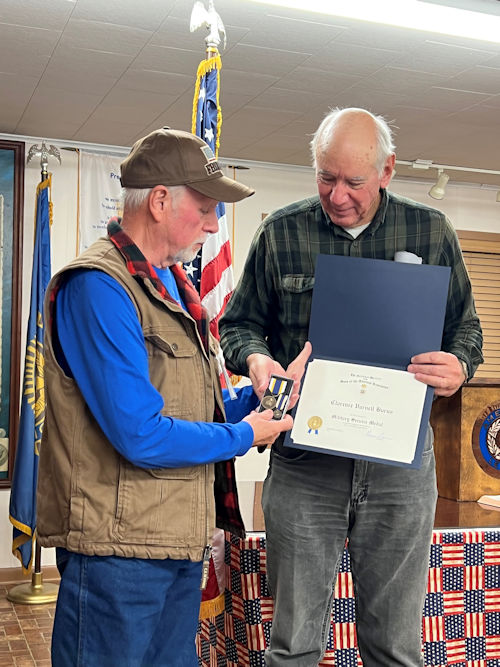 Registrar Dennis Beckham presents the Military Service Medal to President Clarence Burns.