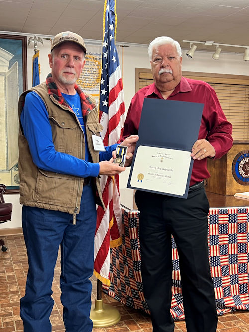 Registrar Dennis Beckham presents the Military Service Medal to Vice President Larry Joe Reynolds.